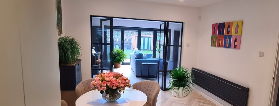 Completed garage conversion to dining room extension – view from sitting room through glass doors with seamless garden connection – HomeExtensionsRUs build project management