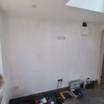 Internal view of the garage during construction, showing completed insulation, flooring, windows and doorway nearing completion