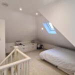 Finished loft bedroom view from the box dormer window showing new wall finishes, ceiling transition and stairwell