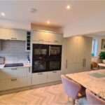 Completed renovation showing modern kitchen with herringbone flooring, new counters and improved natural light